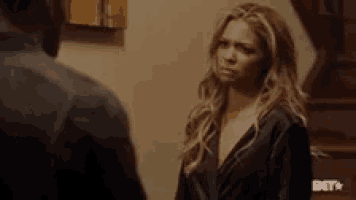 a man and a woman are standing next to each other in a room and looking at each other .