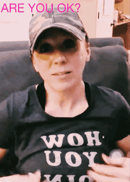 a woman wearing a hat and a shirt that says " are you ok " on it