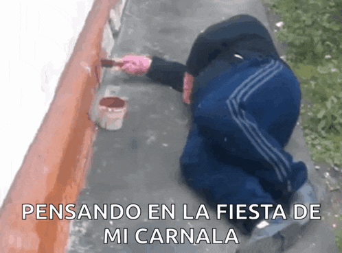 a man is kneeling down and painting a wall with the words " pensando en la fiesta de mi carnal " written below him