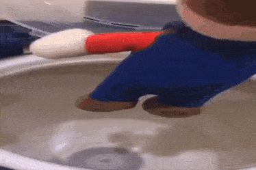 a stuffed mario is sitting in a washing machine with water coming out of it .