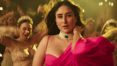 a woman in a pink dress is dancing in front of a crowd of people