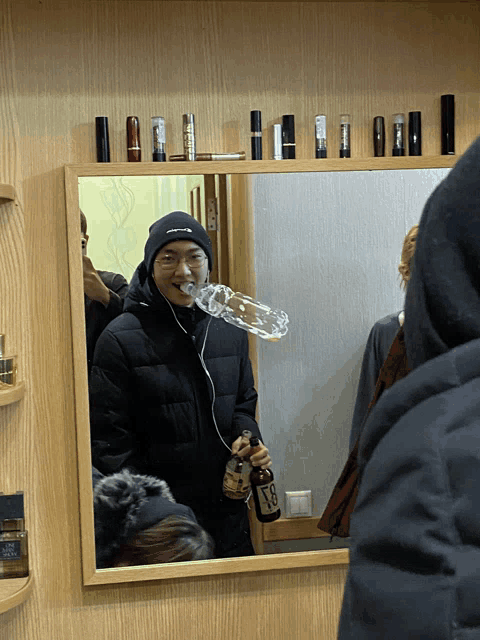 a man in a black jacket is holding a bottle of v8 in front of a mirror