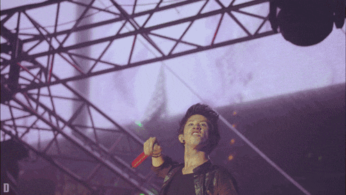 a man singing into a microphone with the letter d in the bottom right corner
