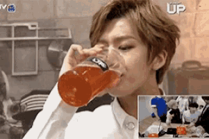 a young man is drinking from a glass with the word up in the background