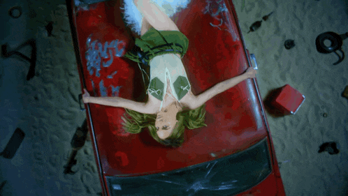 a woman laying on top of a red car