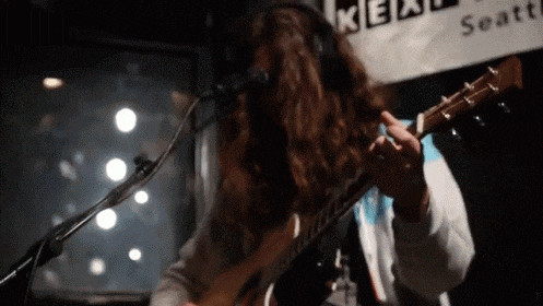 a woman is playing a guitar in front of a sign that says kea