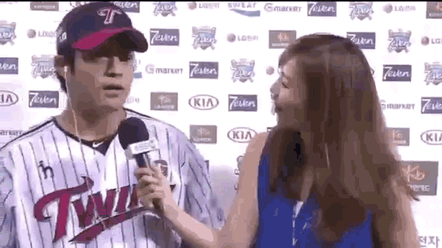 a woman is talking to a baseball player who is wearing a twins jersey