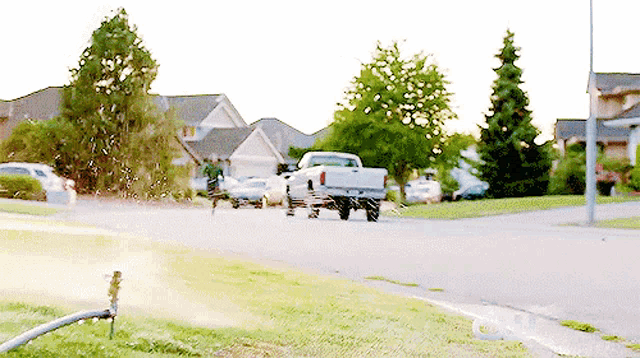a white truck is parked on the side of the road in a residential neighborhood