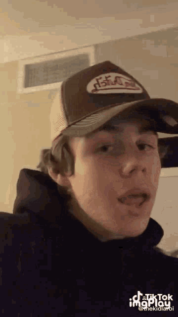 a young man wearing a trucker hat and a black hoodie .