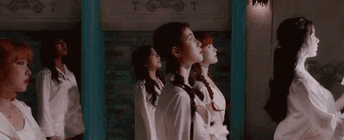 a group of women are standing in front of a blue wall and looking up