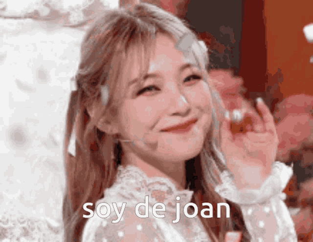 a woman in a white dress is smiling with the words soy de joan written above her .