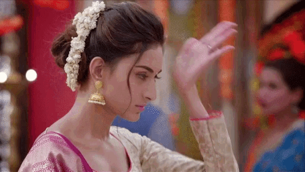 a woman with a bun and earrings is dancing in a room .