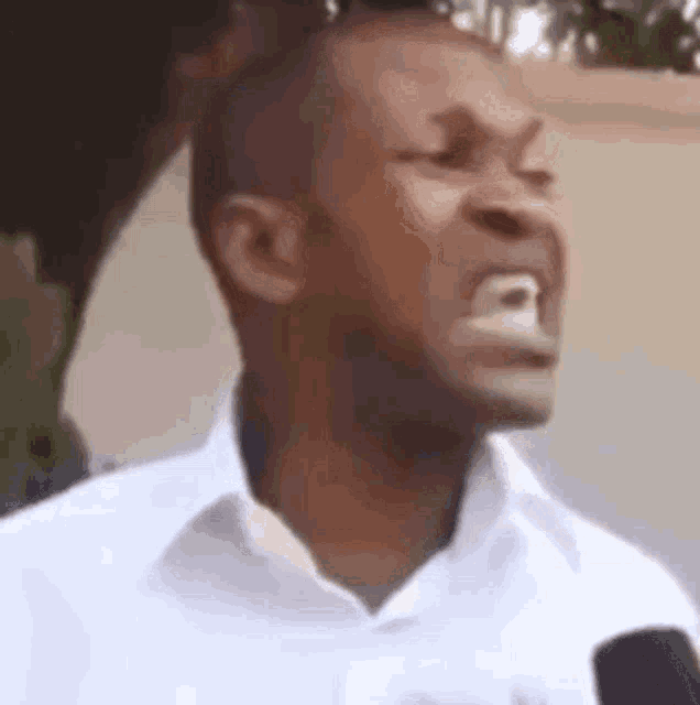 a man in a white shirt is making a funny face with his mouth open .
