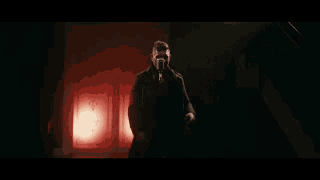 a man in a suit singing into a microphone in a dark room