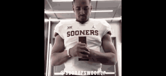 a man in a sooners jersey looks down at something