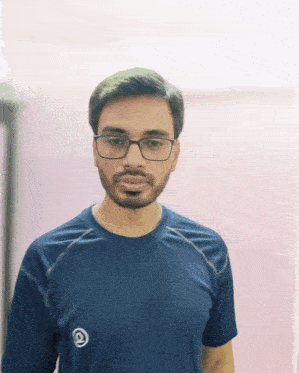 a man wearing glasses and a blue shirt with a white circle on the front