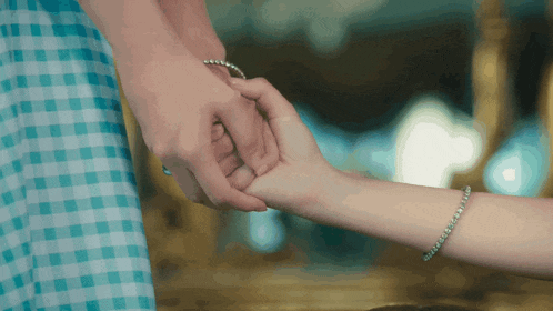 a woman wearing a bracelet on her wrist holds the hand of another woman