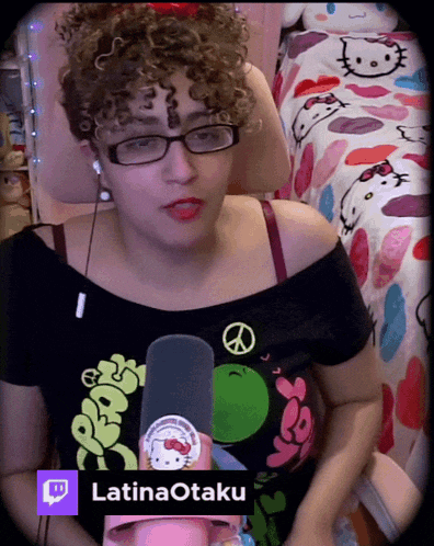 a woman with curly hair and glasses is holding a microphone and has the name latinaotaku below her
