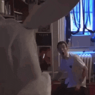 a man is standing in a dark room with a blue light shining on him .