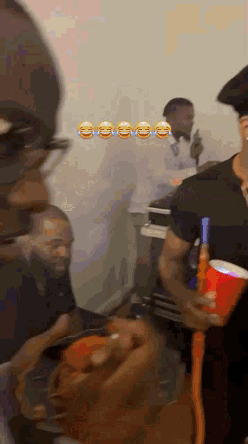 a man in a black shirt is holding a red cup and bottle