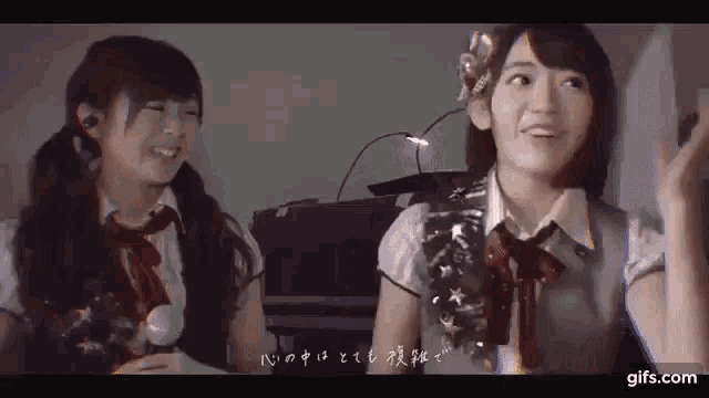 two girls are sitting next to each other in a dark room and smiling .