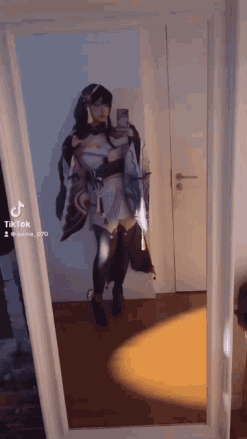 a woman is taking a selfie in front of a mirror while wearing a cosplay costume .