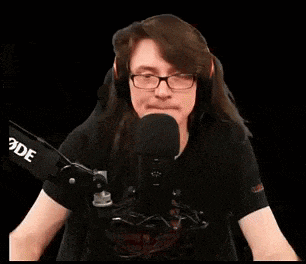 a woman wearing glasses and headphones is sitting in front of a microphone and says eat my whole ass .