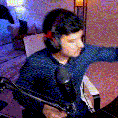 a man is wearing headphones and holding a microphone while sitting in front of a computer .