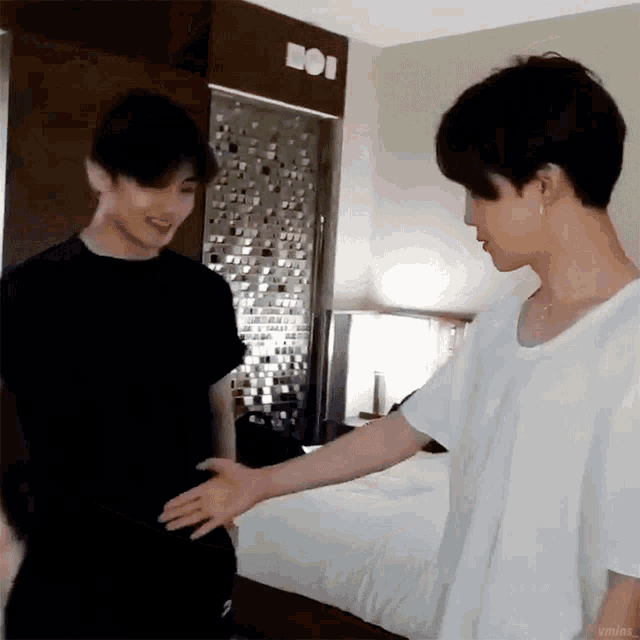 two young men are standing next to each other in a room shaking hands .