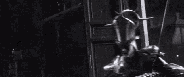 a man in a hood is holding a woman in his arms in a dark room .