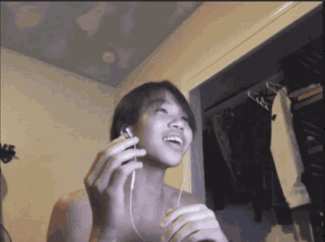 a young girl wearing headphones is singing in front of a closet