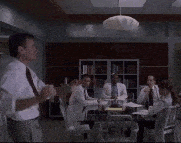 a man in a white shirt is giving a presentation to a group of people