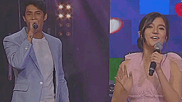 a man in a suit is singing into a microphone next to a woman in a pink dress holding a microphone .