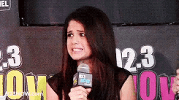 a woman is holding a microphone in front of a sign that says 2.3 on it