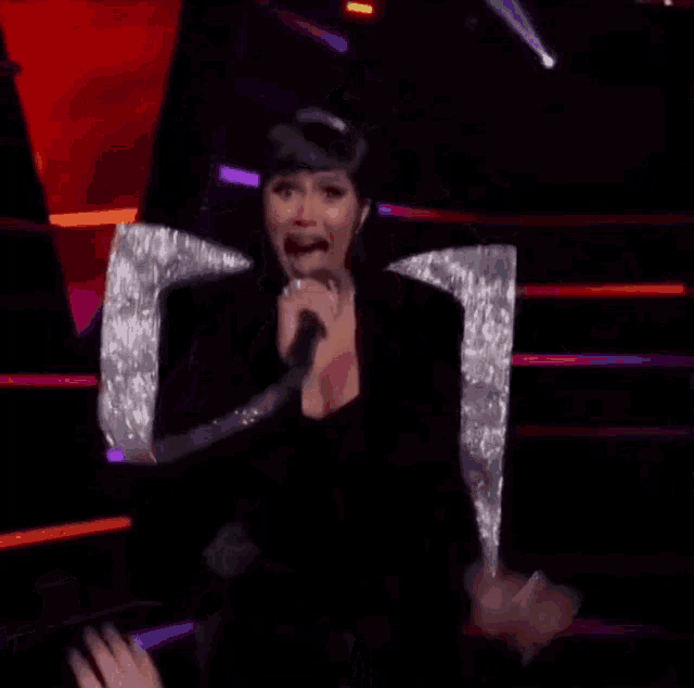a woman is singing into a microphone on a stage while dancing .