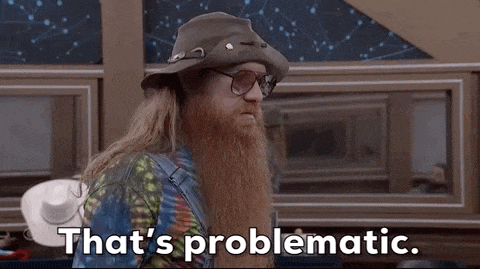 a man with a beard and glasses is wearing a hat and a tie dye shirt .