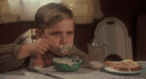 a young boy is sitting at a table eating a bowl of food