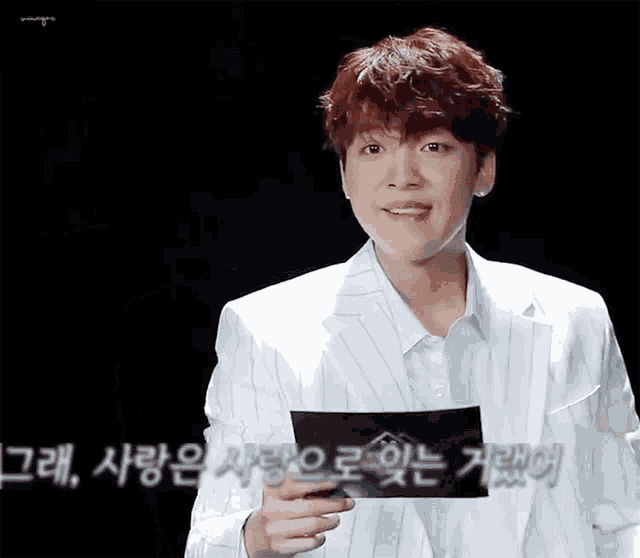a man in a white suit is holding a piece of paper in his hand