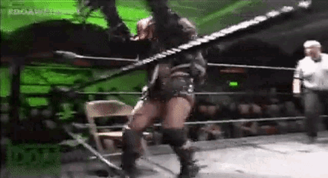 a woman is standing in a wrestling ring holding a rope and a chair .
