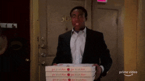 a man in a suit is holding three boxes of pizza in front of a door .
