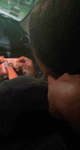 a woman sitting in a car holding a piece of money