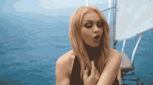 a woman in a black top is standing on a boat in the water