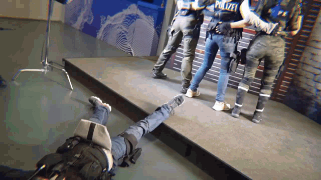 a group of police officers are standing around a person laying on the ground