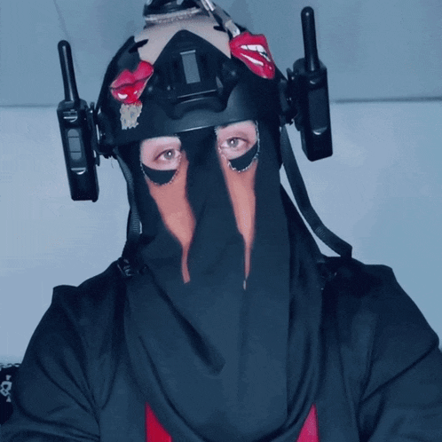 a person wearing a black mask with two walkie talkies attached to their head