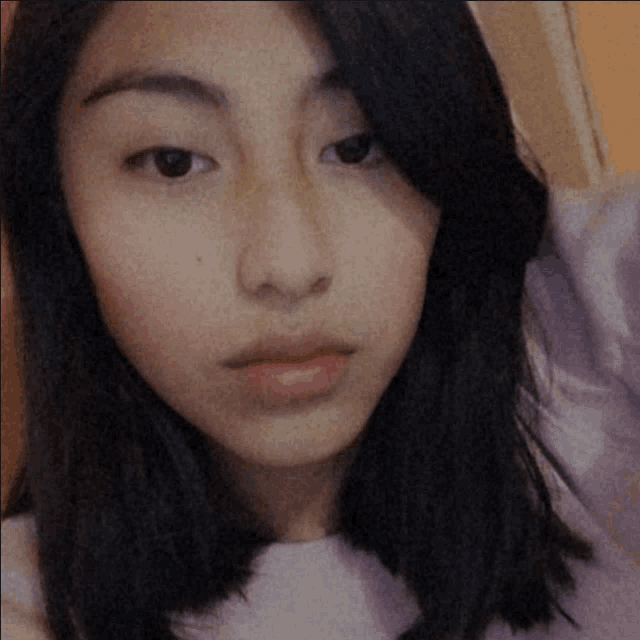 a close up of a young woman 's face with a purple shirt on