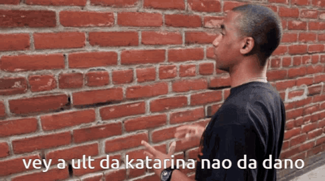 a man standing in front of a brick wall with the words " vey a ult da katarina nao da dano " above him