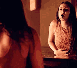 a woman is standing in front of a mirror with a stomach ache