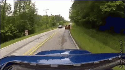 a blue car is driving down a road with a sign that says no trucks