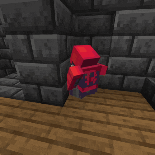 a red block with a skull on it is sitting on a wooden floor in front of a brick wall