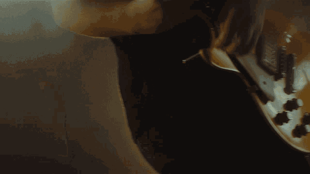 a close up of a person playing a guitar with a black shirt on